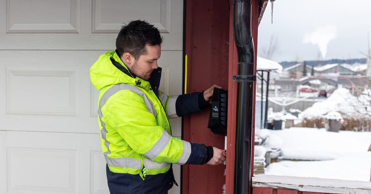 Mannlig elektriker monterer en elbillader på en garasjevegg Mannlig elektriker monterer en elbillader på en garasjevegg