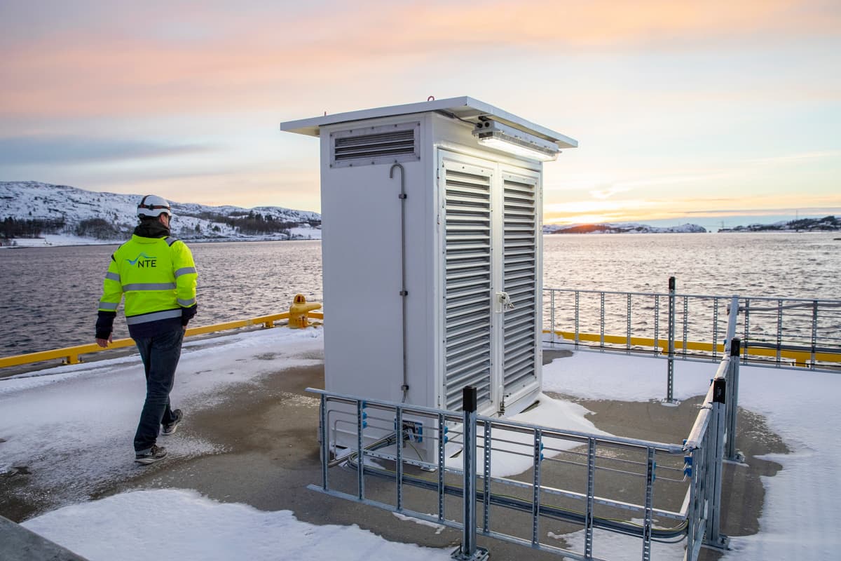 NTEs forste produksjonsanlegg for gront hydrogen NTE 03510 Mann i arbeidskær og hjelm går forbi en hvit aluminiumskasse