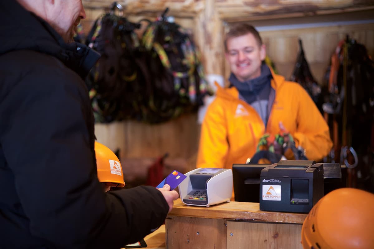 Betaling med kort Mann står bak en disk mens en annen mann skal betale med visakort på en betalingsterminal