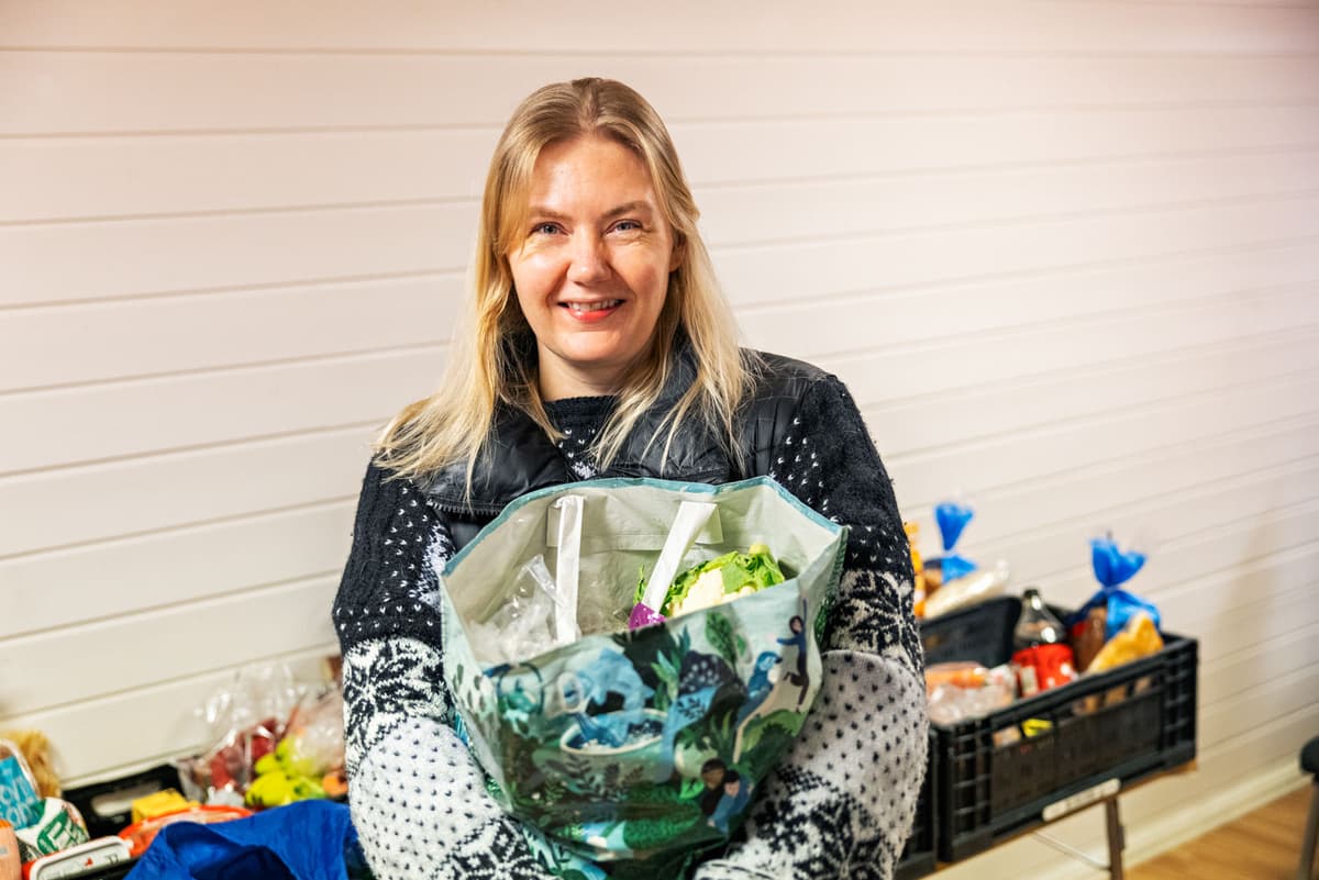 Julie setter stor pris på Hjelp mæ å hjelpe Dame holder fram en pose med mat og smiler. Foto.