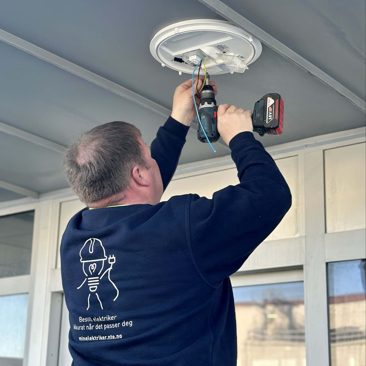 Elektriker som monterer armatur Bilde av elektriker som monterer lysarmatur
