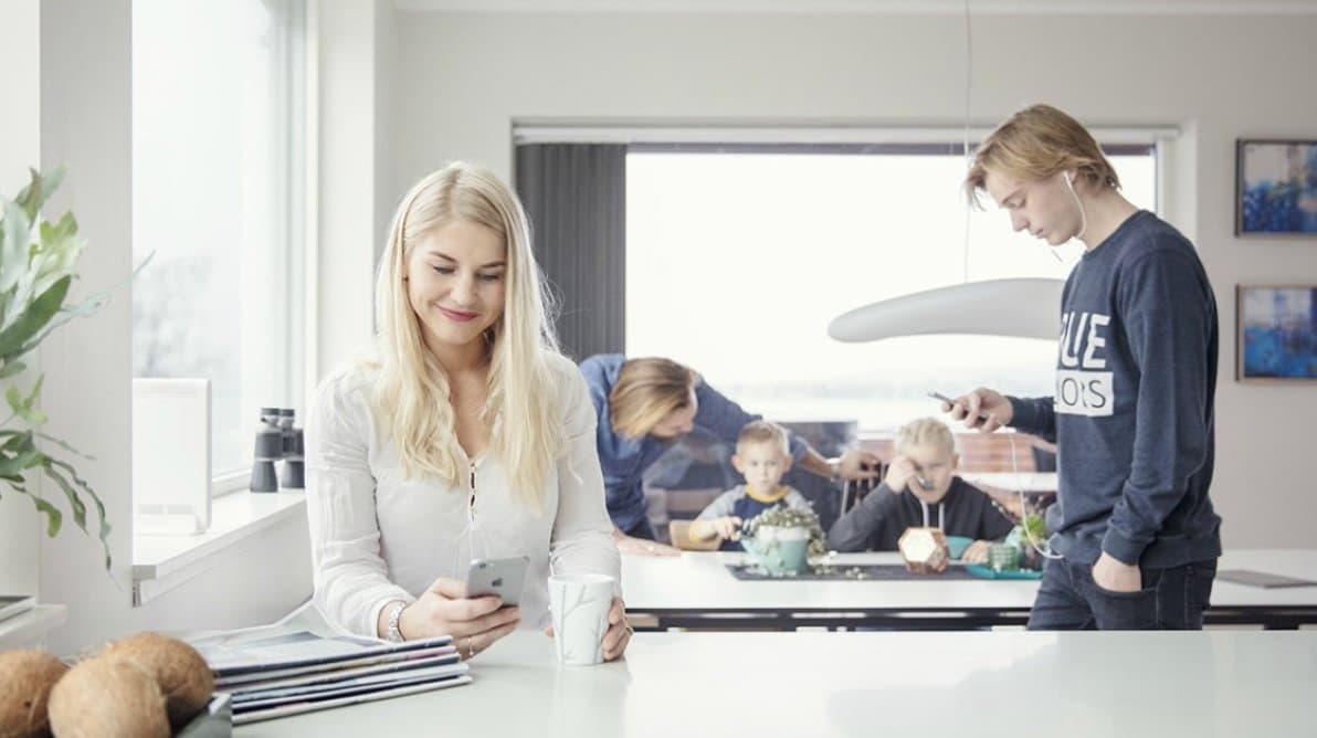 Bilde av en stor familie der far snakker med de to yngste barna, mens mor og sønn ser på sin telefon Bilde av en stor familie der far snakker med de to yngste barna, mens mor og sønn ser på sin telefon