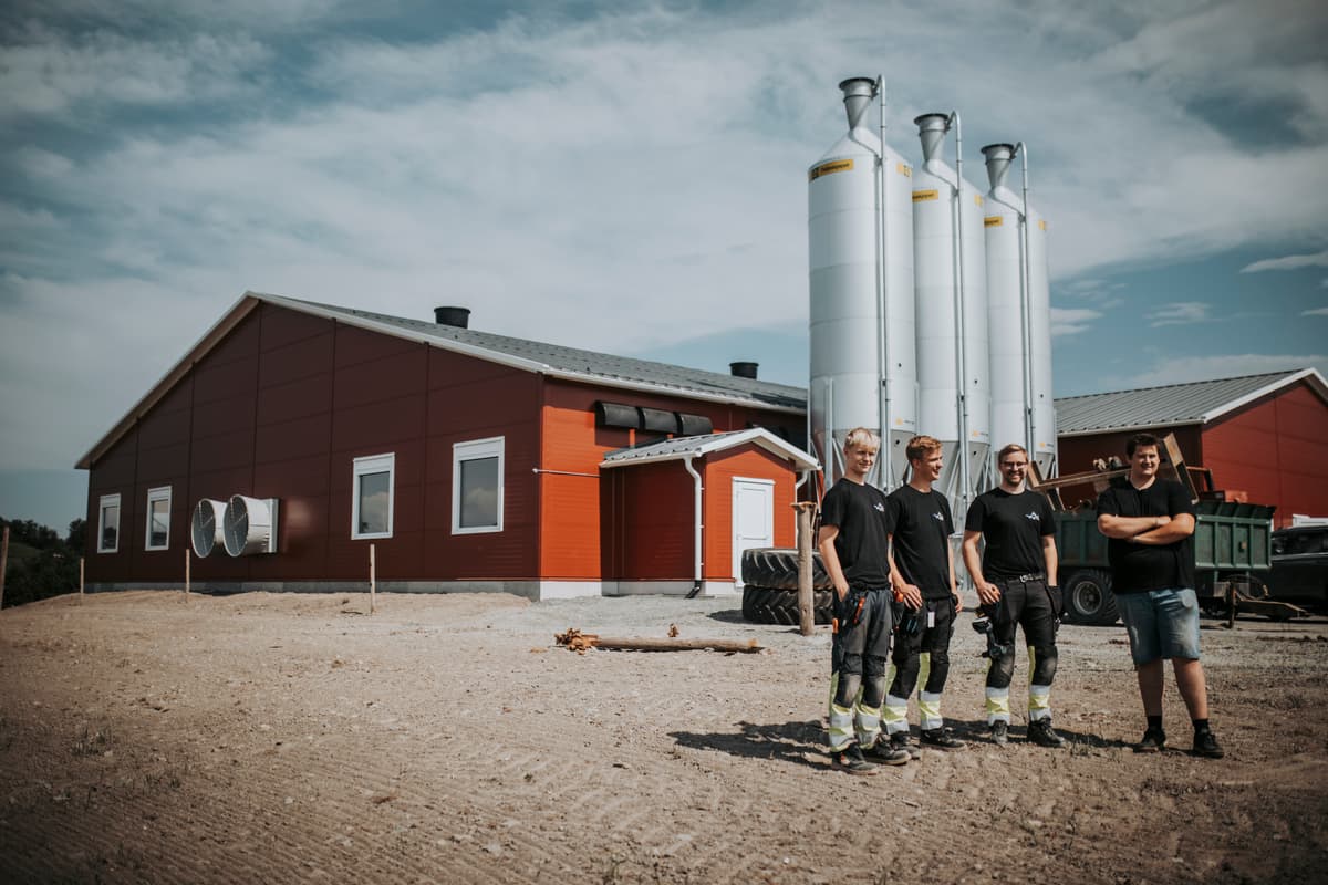 utendørsbilde av elektrikere og kunde Fire menn utenfor et kyllingfjøs med siloer