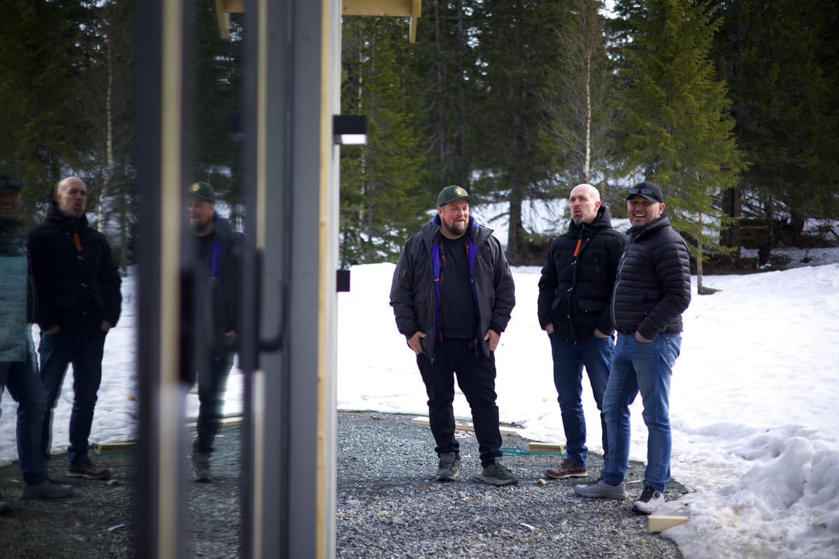 Utenfor hytte ved Teveltunet Tre menn står utenfor en hytte. Snø og skog i bakgrunnen.