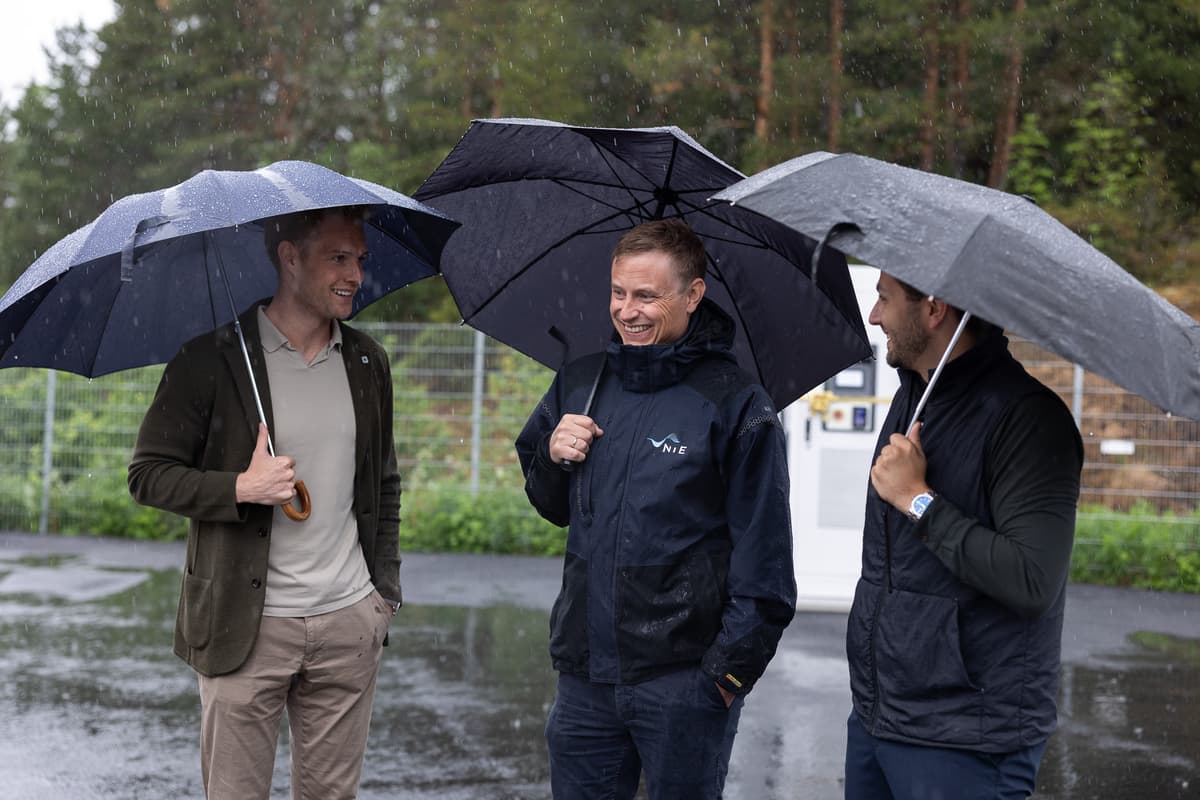 Sindre, Ronny og Sverre Tre smilende menn i samtale. Alle holder hver sin paraply og regnet øser ned.