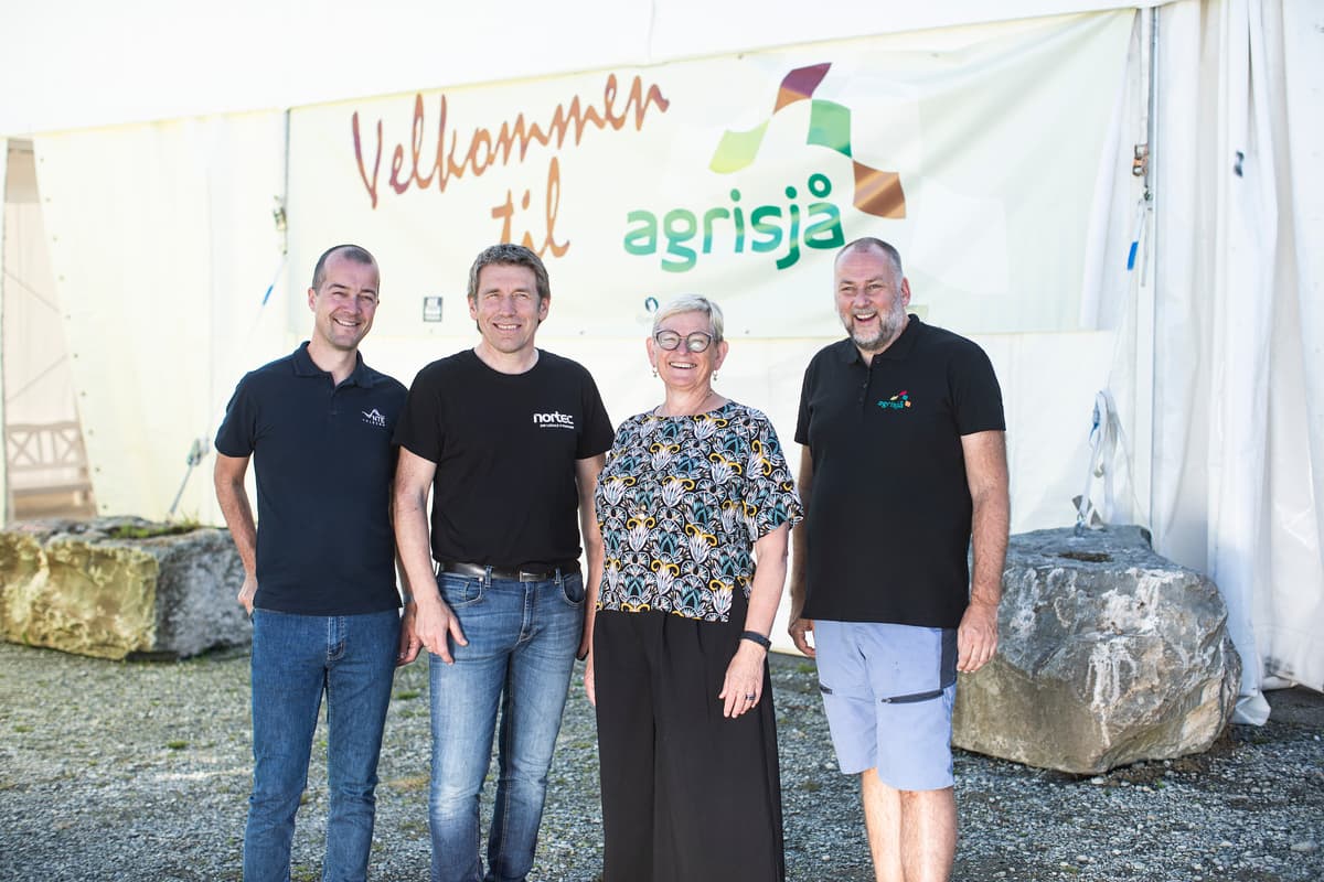 3 menn og en kvinne smiler foran et skilt det står Velkommen til agrisjå på 3 menn og en kvinne smiler foran et skilt det står Velkommen til agrisjå på