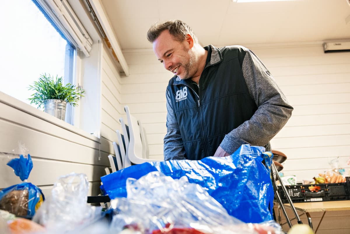 Kai Arne Berg henter ut matvarer hos Hjelp mæ å hjelpe. Mann ser oppi en pose med matvarer. Foto.